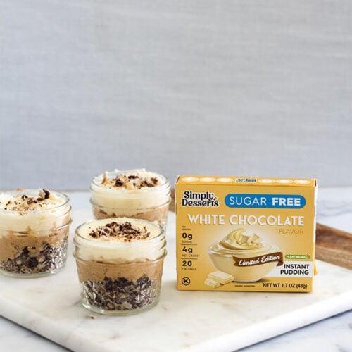 Simply Desserts Sugar-Free White Chocolate Pudding box displayed next to prepared White Chocolate Caramel Wafer Gu Pots on a marble surface
