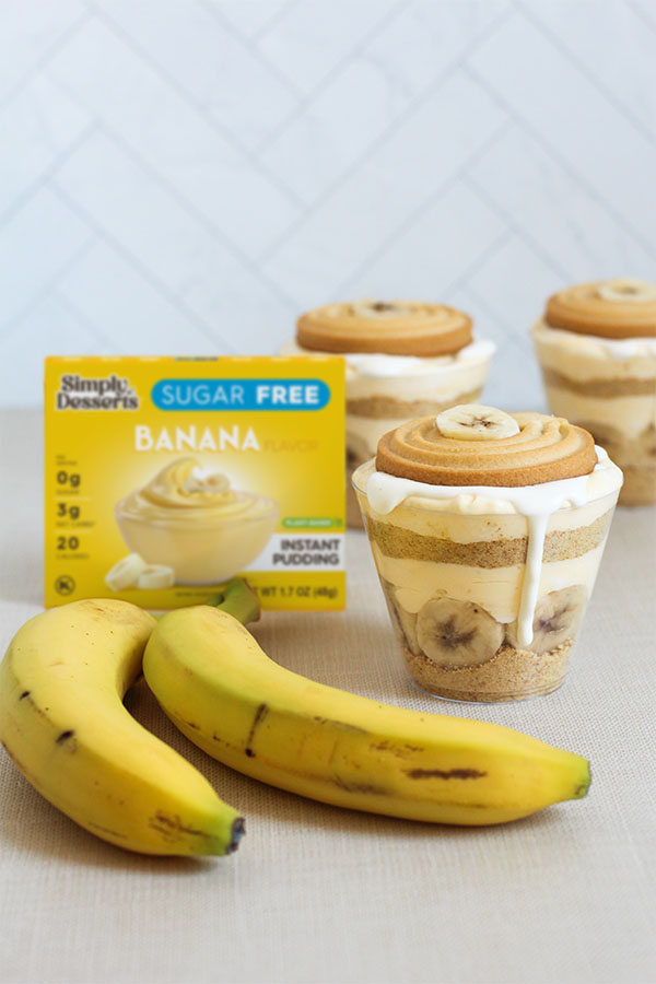 Row of banana pudding cups with visible layers of graham cracker crumbs, banana slices, and pudding