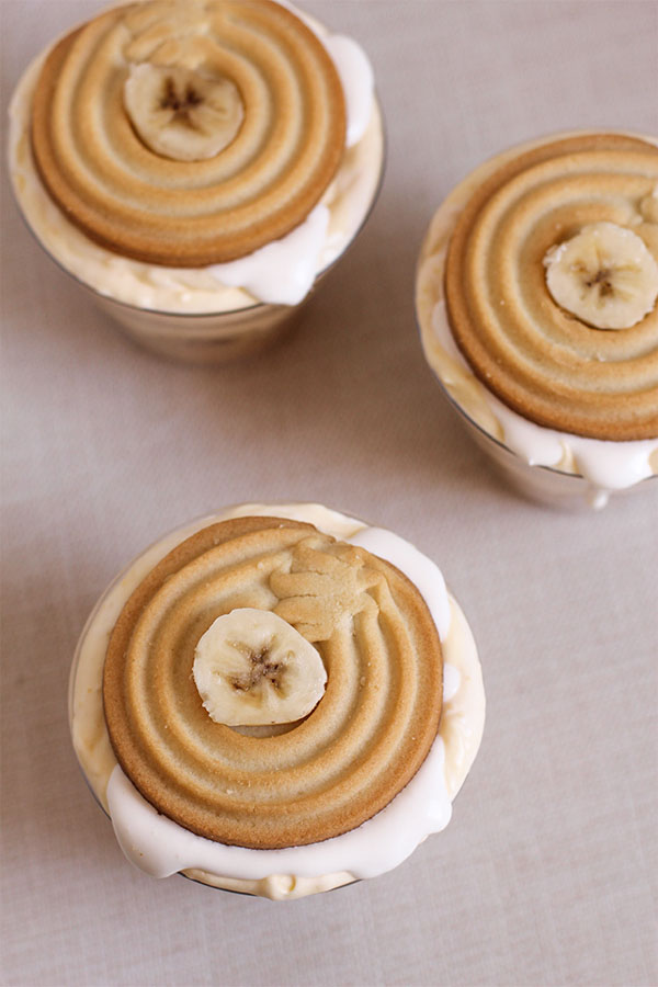 Top-down view of four banana pudding cups layered with cool whip and banana slices