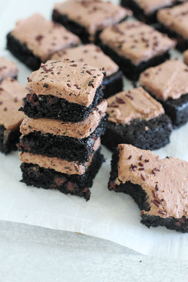 Brownies stacked on parchment with one piece bitten, showing the rich moist texture