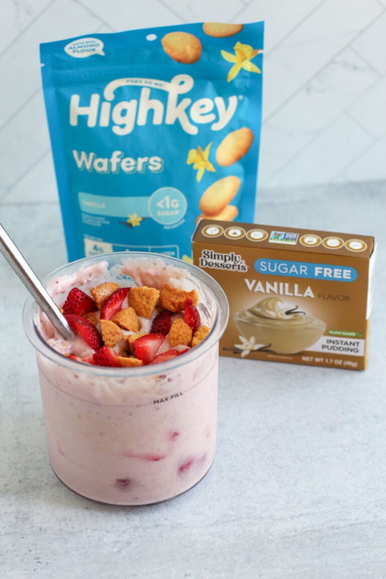 Strawberry shortcake ice cream in a glass bowl with a spoon, placed in front of Simply Delish Vanilla Pudding and Highkey Wafers packaging Featured Image