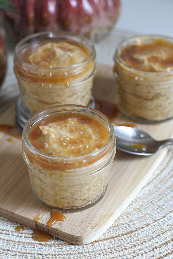 Small glass jars filled with creamy salted caramel pudding topped with caramel drizzle