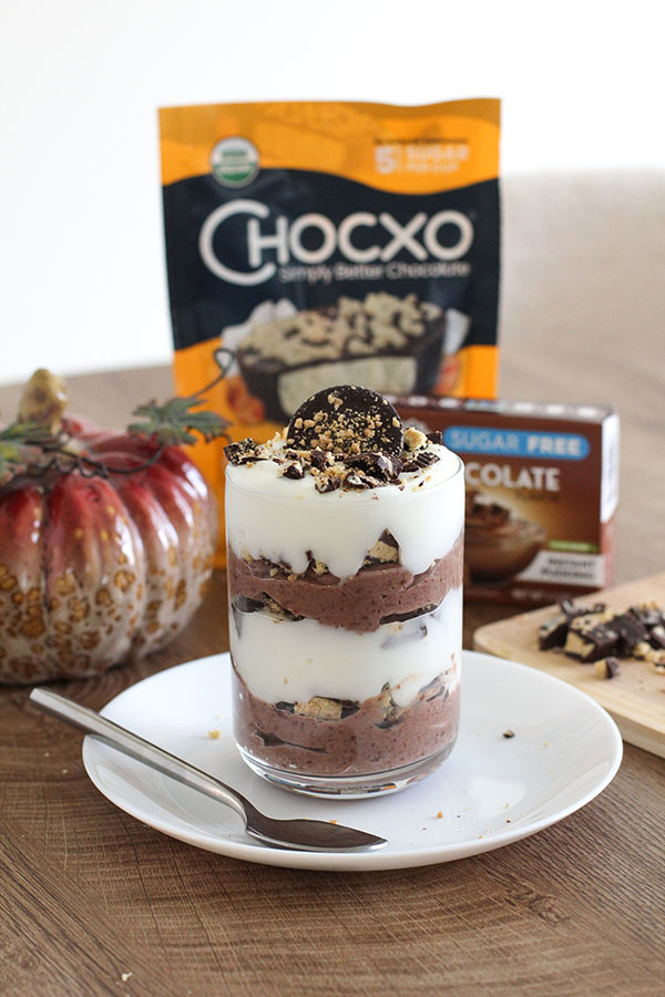 Chocolate coconut caramel parfait served in a glass with Chocxo chocolate and Simply Desserts pudding in the background