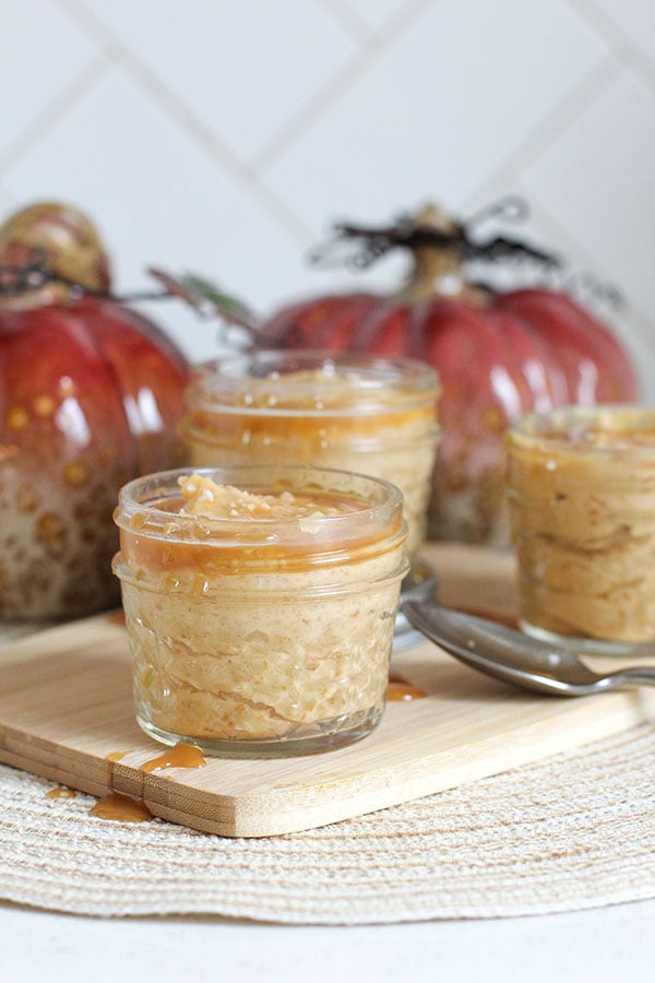Salted caramel pudding in jars on a wooden board with caramel sauce