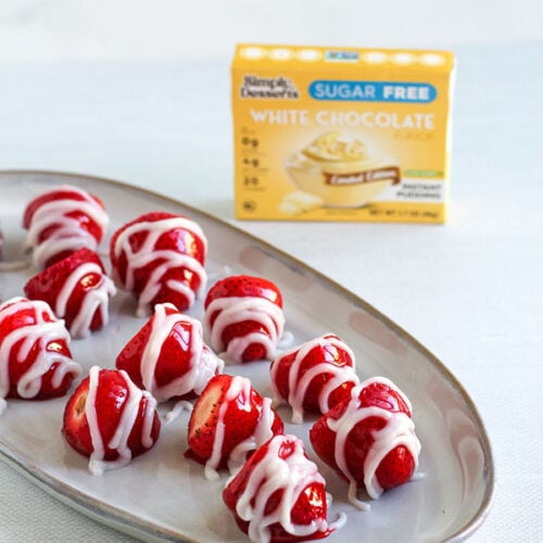 Plate of strawberries drizzled with white chocolate pudding beside Simply Desserts box