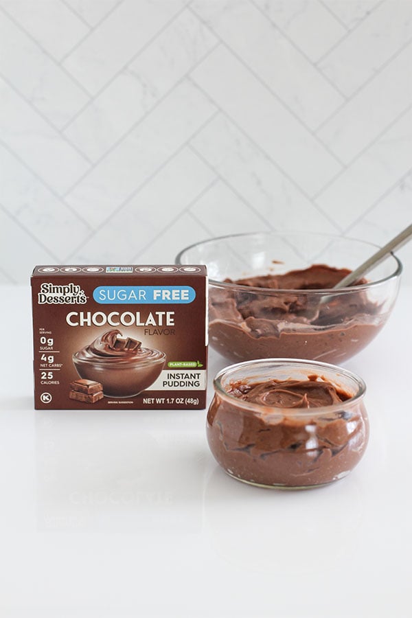 Simply Desserts Sugar-Free Chocolate Pudding box displayed beside bowls of freshly mixed chocolate pudding