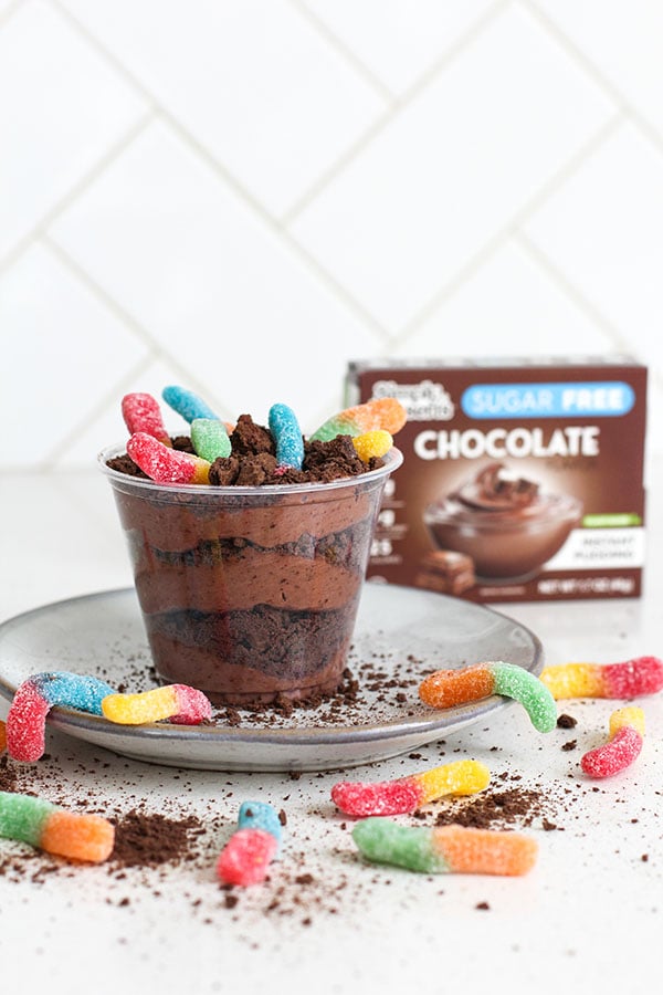 Pudding dirt cup with Simply Desserts Chocolate Pudding box in background and scattered gummy worms