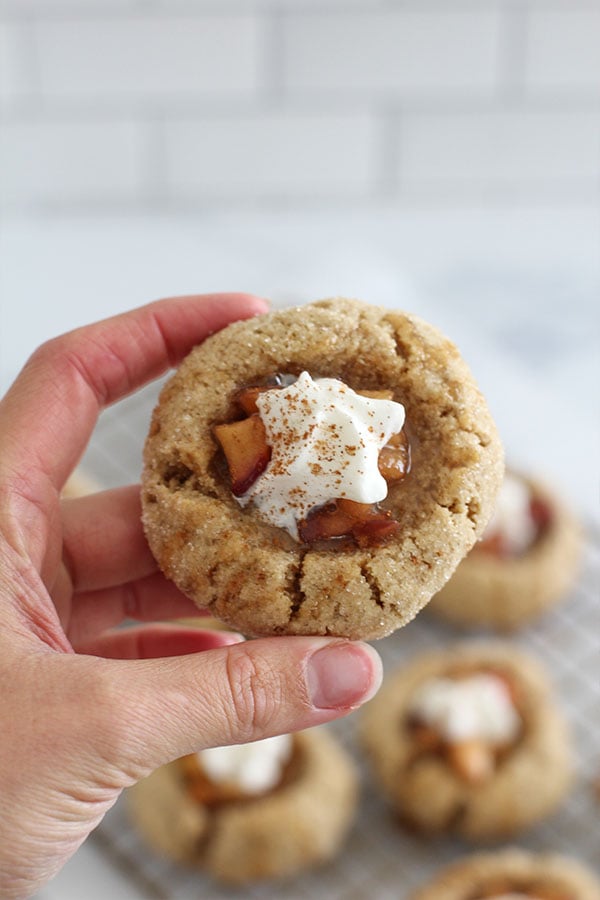 Hand holding a single apple pie cookie showing the gooey filling