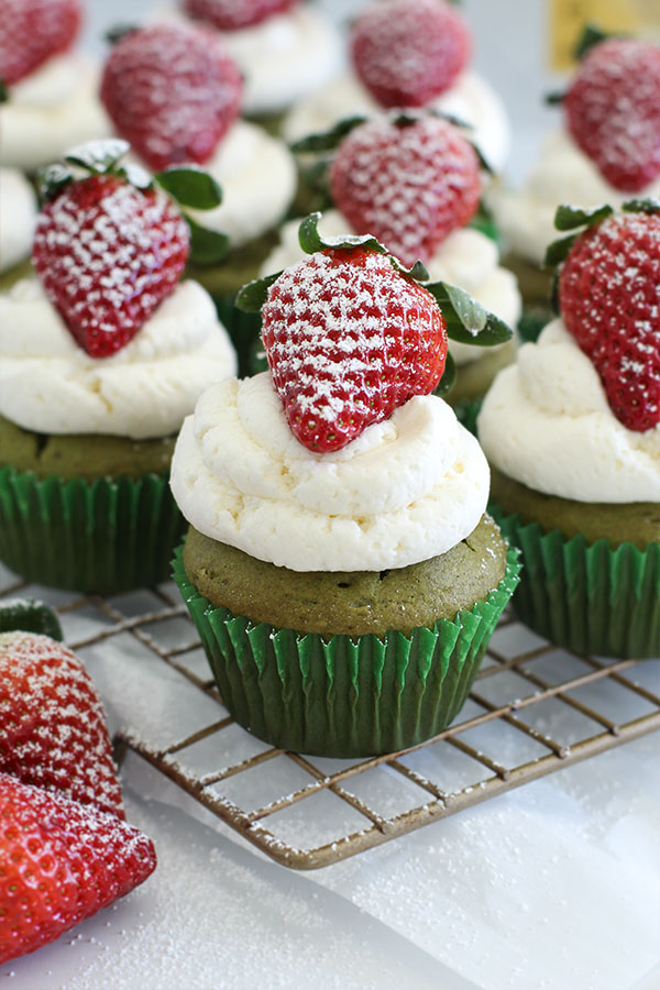 Close-up of matcha cupcakes with creamy white chocolate frosting and powdered strawberries